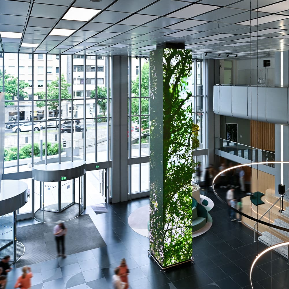 ED-Turm mit grüner Animation im lichtdurchfluteten Foyer des ICON by Covivio Düsseldorf, gesehen von oben.