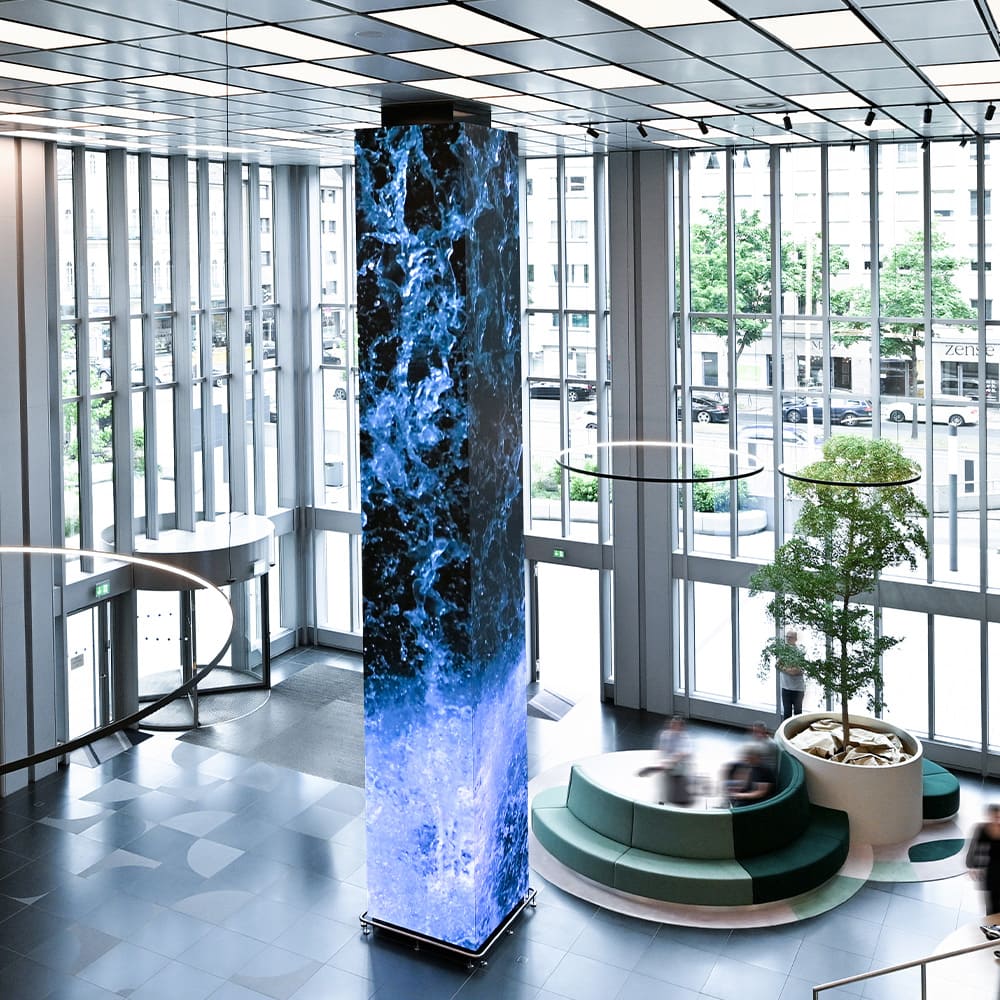 Neun Meter hohes LED-Totem mit Wasserfallanimation im lichtdurchfluteten Foyer des ICON by Covivio Düsseldorf.