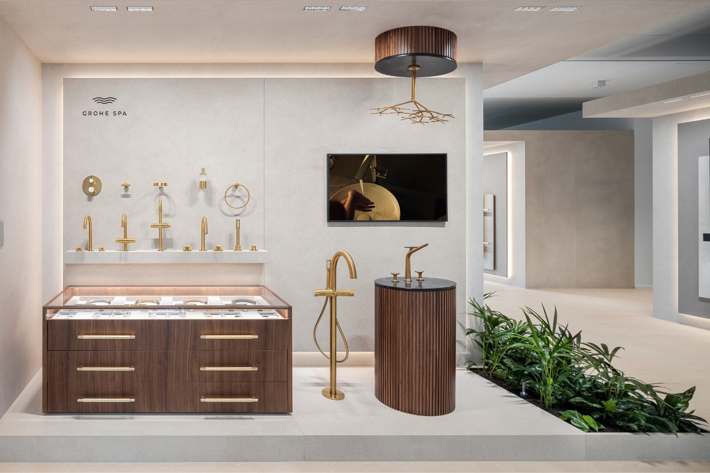 GROHE SPA Präsentationswand mit goldfarbenen Armaturen, Vitrine, Holzwaschtisch und integriertem Bildschirm