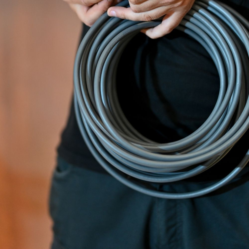 Nahaufnahme von Händen, die ein Kabel fachgerecht aufrollen