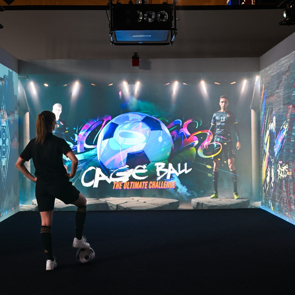 Sportler bei Cage Ball Spiel in beleuchteter digitaler Arena mit großformatigem LED-Wanddisplay und Grafik-Overlay